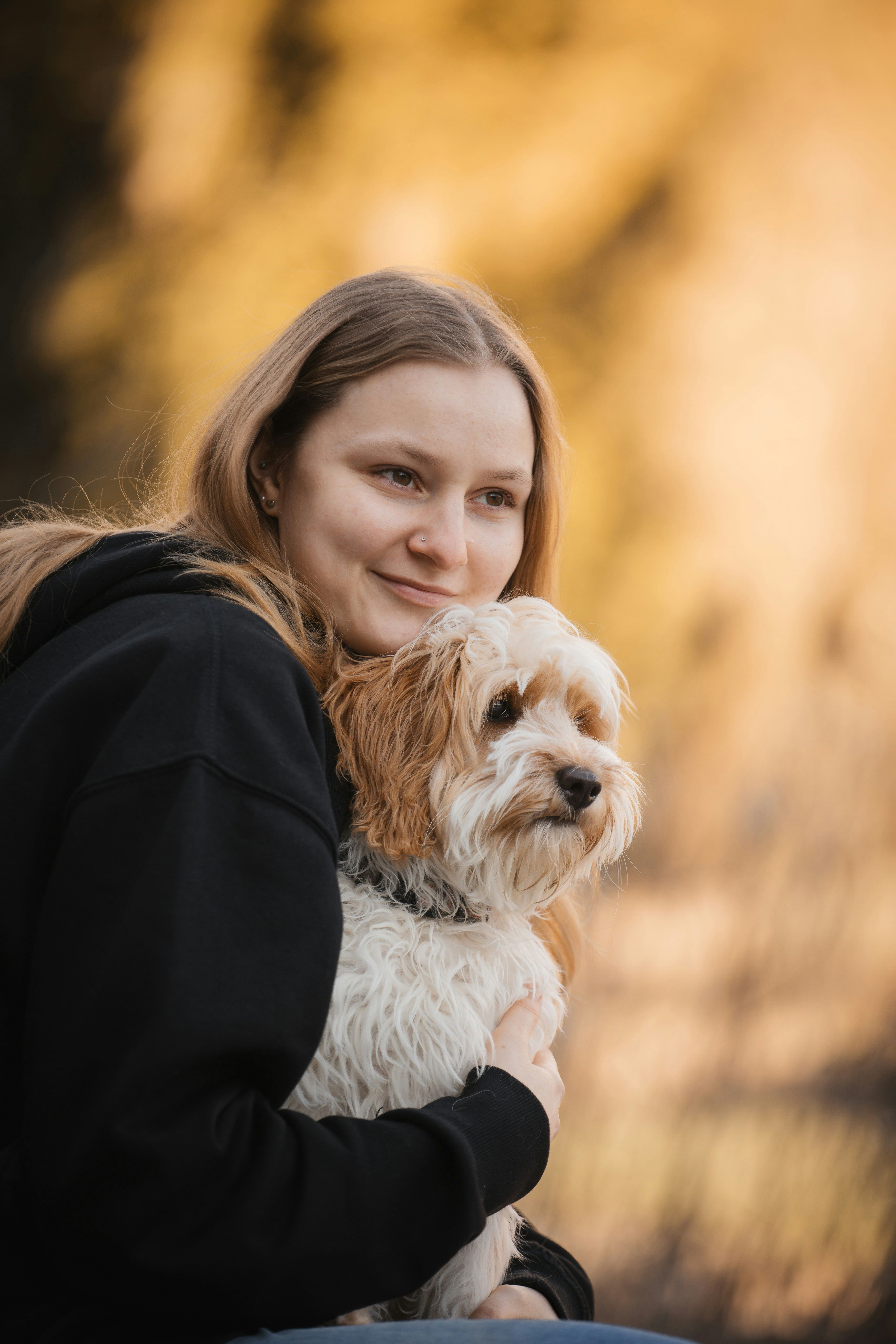 Une jeune femme blonde faisant un câlin à son petit chien